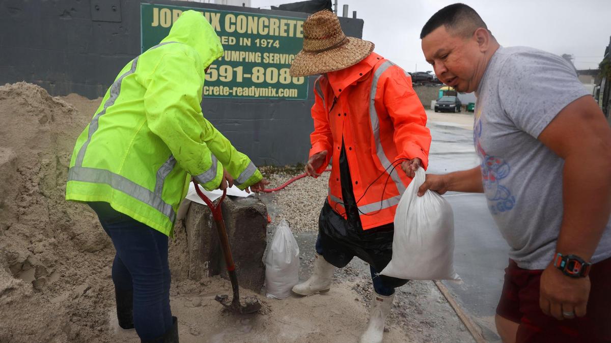 Valdemar Linol left, from Rudy’s Ready Mix packs sandbags for Jose Vanegas, right, in preparation for Hurricane Ian on Tuesday, Sept. 27, 2022, in West Miami-Dade.