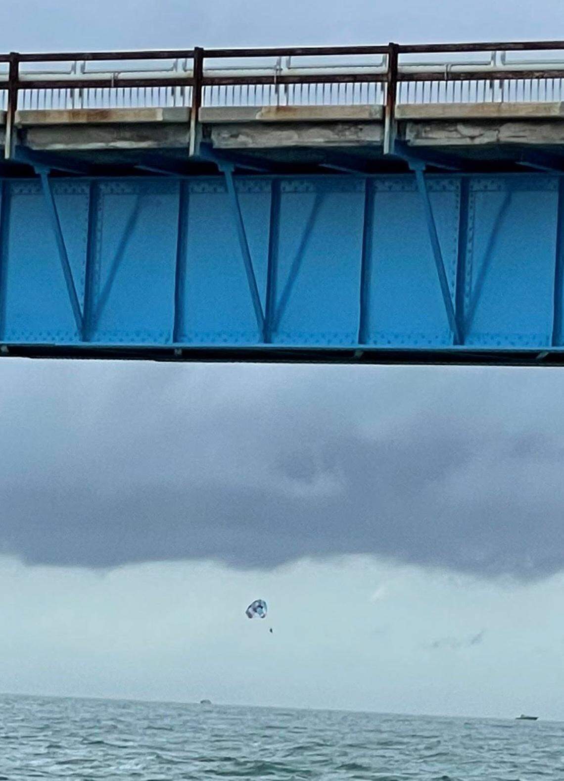 Three people hang from a parasail off the old Seven Mile Bridge in the Florida Keys Monday, May 30, 2022, minutes before a high wind gust prompted the captain of the boat towing them to cut them loose.
