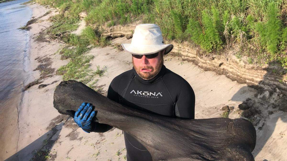 Derek Demeter holds a 50-pound giant Columbian mammoth leg bone he and his diving partner Henry Sadler found on April 25, 2021, while scuba diving in the Peace River in Arcadia, Florida.