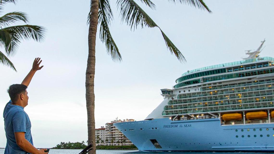 A biker waves to people aboard Royal Caribbean International’s Freedom of the Seas cruise ship as it sets off down Government Cut past South Pointe Park for a simulated voyage leaving from PortMiami in Miami, Florida, on Sunday, June 20, 2021. In accordance with CDC requirements, the purpose of the simulation is to observe the cruise line’s multilayered health and safety measures.