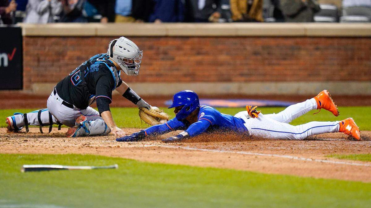 New York Mets’ Francisco Lindor, right, slides past Miami Marlins catcher Jacob Stallings to score on a walk-off single by Eduardo Escobar during the 10th inning of a baseball game Wednesday, Sept. 28, 2022, in New York. The Mets won 5-4. (AP Photo/Frank Franklin II)