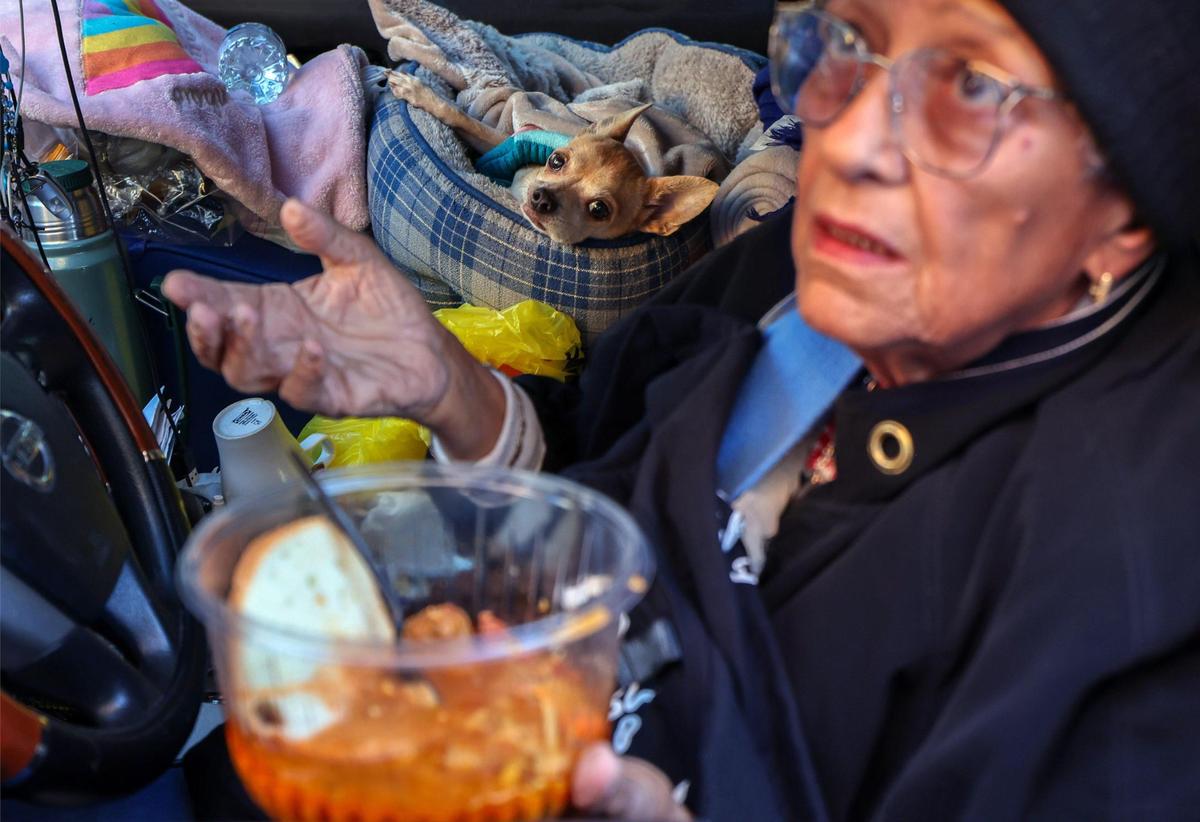 Maria Morales prays before eating her meal as Besito, her pet chihuahua, watches on Thursday, Jan. 9, 2025, in Miami.