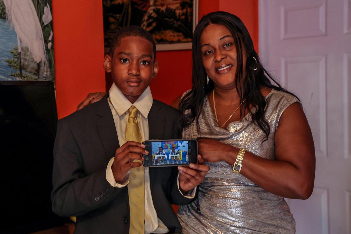 Marie Carmella Baron y su hijo Geovensley Desrosiers sosteniendo una foto de teléfono de los hermanos gemelos Scott (a la izquierda) y Jerry Narcius, hijos de su hermana, que murió luego de dar a luz en Miami el año pasado.