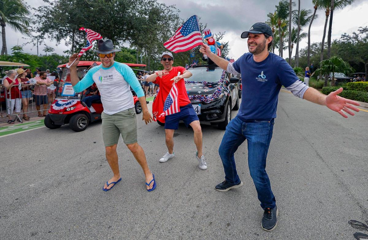 Michael Leigh, Andrew Arce and Alejandro Servalli, left to right, dance along the parade route on Crandon Boulevard as they celebrate Independence Day during the 66th Annual Key Biscayne Fourth of July Parade on Key Biscayne, Florida on Friday, July 4, 2025.