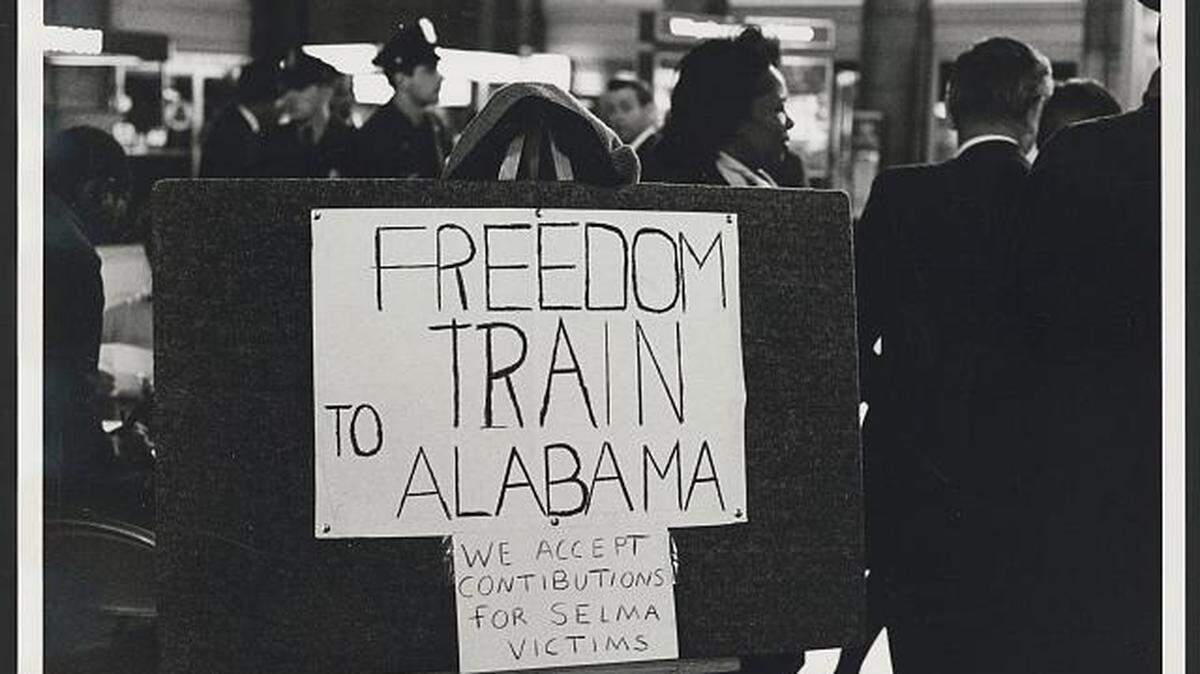 This Library of Congress photograph shows participants of the 1965 civil rights march following the Selma attacks: "We accept contributions for Selma victims, ” the sign reads.