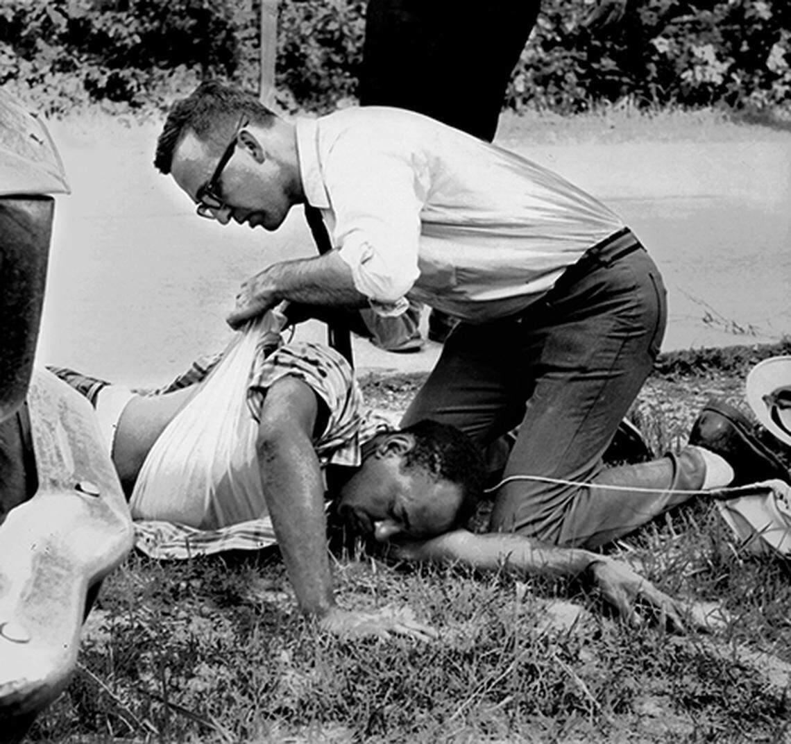 Sherwood Ross attends to James Meredith after he was shot June 6, 1966 on Highway 51 about two miles south of Hernando, Miss. Meredith was leading a 'March Against Fear' to encourage blacks to exercise their voting rights. Meredith, who defied segregation to enroll at the University of Mississippi in 1962, completed the march from Memphis, Tenn., to Jackson, Miss., after treatment of his wounds. Aubrey James Norvell spent 18 months and 24 days of a two-year sentence in the Mississippi State Penitentiary at Parchman for the shooting. Ross, a 33-year-old radio newsman from Washington D.C., said he was acting as Meredith's press spokesman as well as reporting for stations in Washington and New York. (By Ramon Himel / The Commercial Appeal )