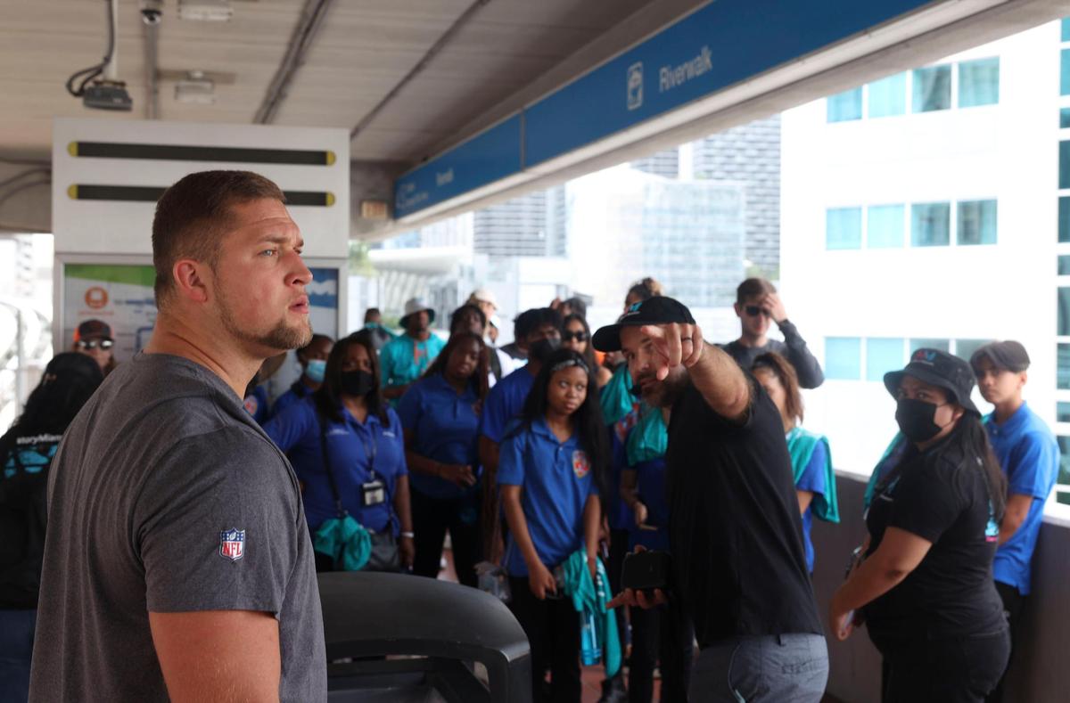 Ben Stille, a member of the Miami Dolphins rookie class, left, and youth from Miami Police Athletic League participate in a historic walking tour of Downtown Miami on Wednesday, June 15, 2022, beginning with tour leaders at the History Miami Museum.