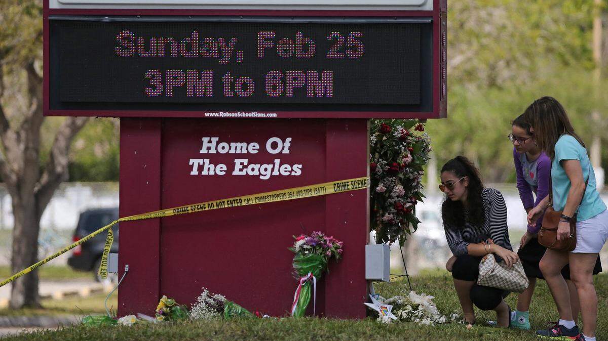 Mourners bring flowers as they pay tribute at a memorial for the victims of the shooting at Marjory Stoneman Douglas High School on Sunday, Feb. 25, 2018 as parents and students returned to the school for the first time since the shooting.