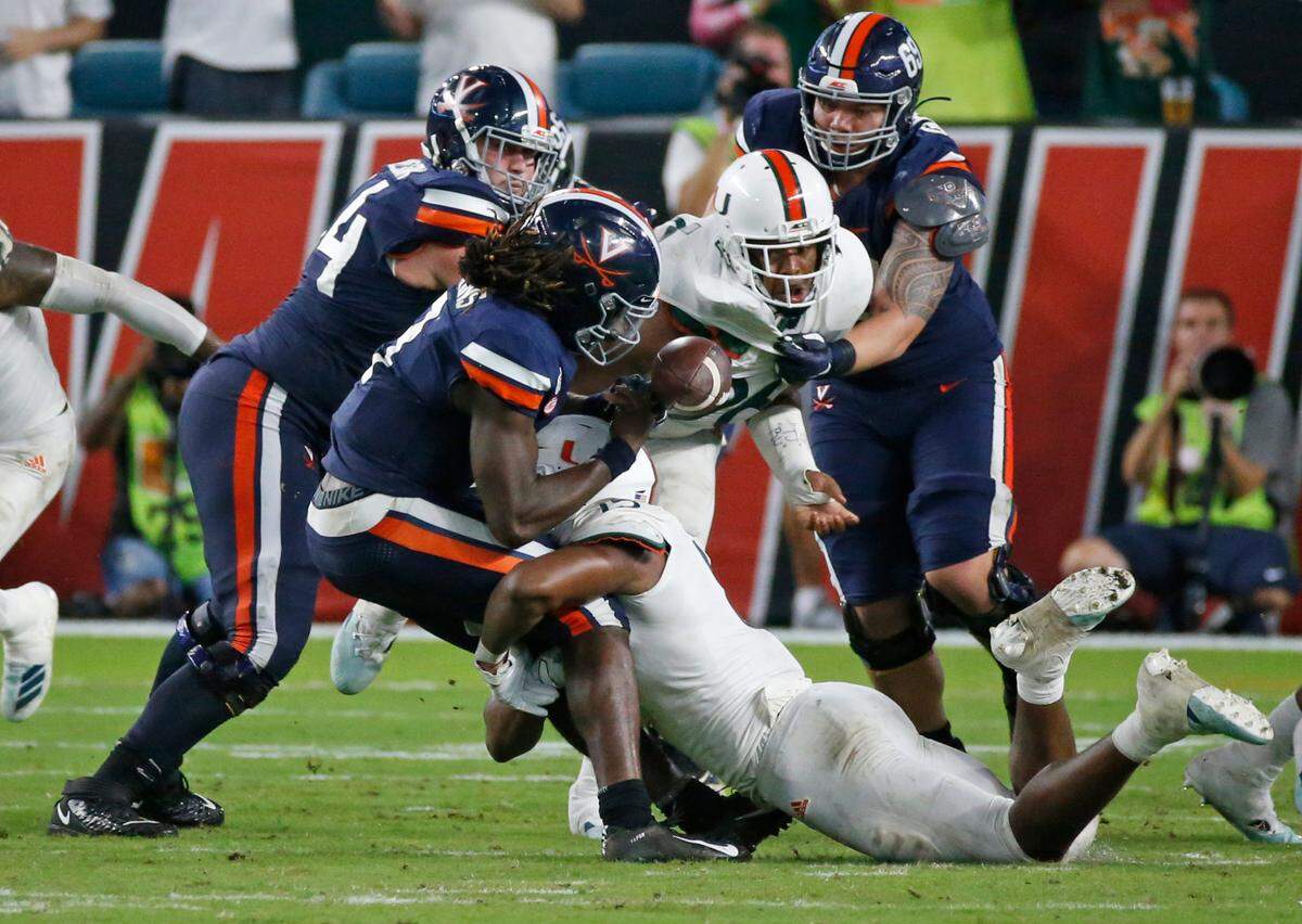 Miami Hurricanes defensive lineman Gregory Rousseau (15) sacks Virginia Cavaliers quarterback Bryce Perkins (3) and causes him to fumble the ball in the fourth quarter as the University of Miami host the Virginia Cavaliers at Hard Rock Stadium in Miami Gardens on Friday, October 11, 2019.
