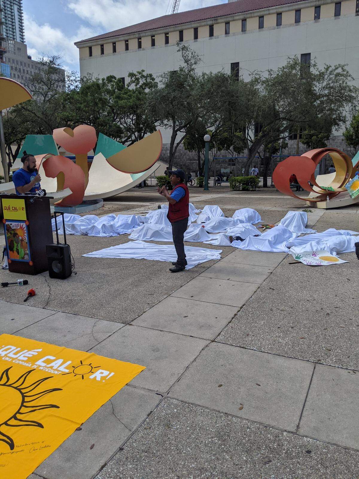 Workers lay on the ground under white sheets to call attention to the 34 people a year, on average, who die of heat-related illnesses in Miami-Dade County.