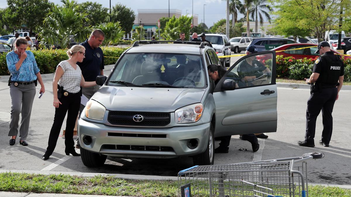 Fort Lauderdale police investigate a car in the parking lot of a shopping plaza at 2510 West Broward Blvd. where a mother was shot by her young child Thursday afternoon.