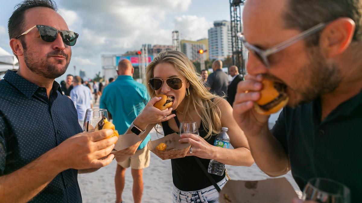 De izquierda a derecha: Brad Milhauser, Erika Milhauser y Todd Rosenberg asisten al Burger Bash del South Beach Wine & Food Festival en Miami Beach, Florida, el jueves 20 de mayo de 2021.