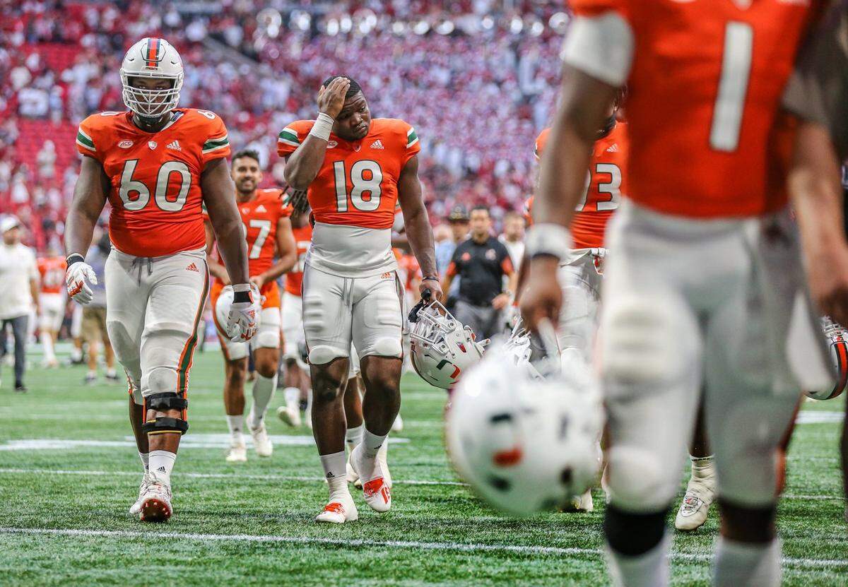 Miami Hurricanes offensive lineman Zion Nelson (60) and linebacker Tirek Austin-Cave (18) walks off the field after losing to Alabama Crimson Tide 44-13 at Mercedes-Benz Stadium in Atlanta on Saturday, September 4, 2021.