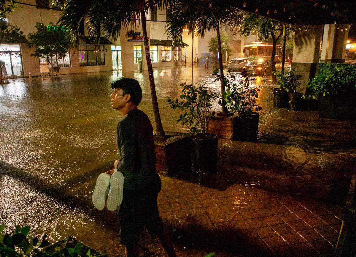 A man looks at the rain as streets flood in Brickell, Miami, on Wednesday, Nov. 16, 2023.