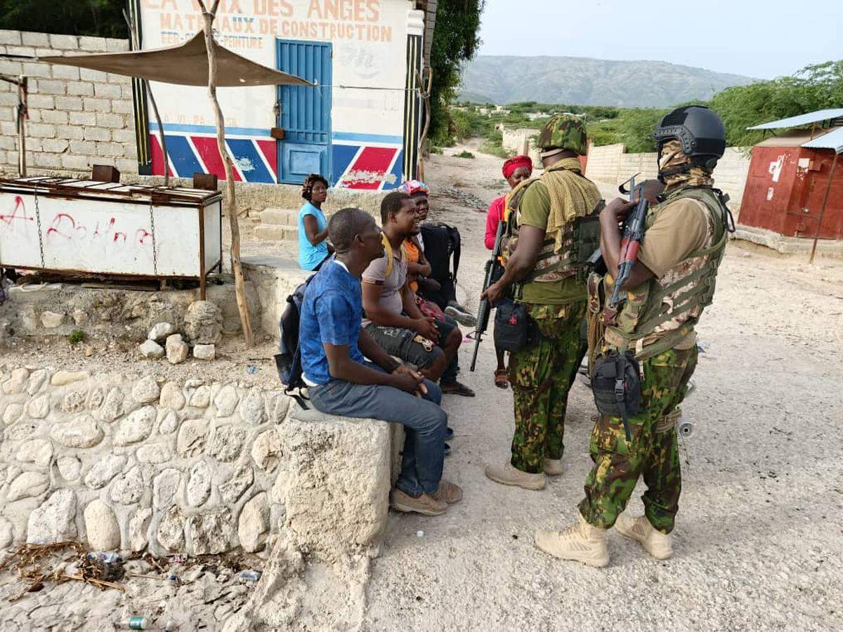 Kenyan police officers speaking to residents of Ganthier in July 2024 after gaining access to the community amid an active attack by the 400 Mawozo gang.