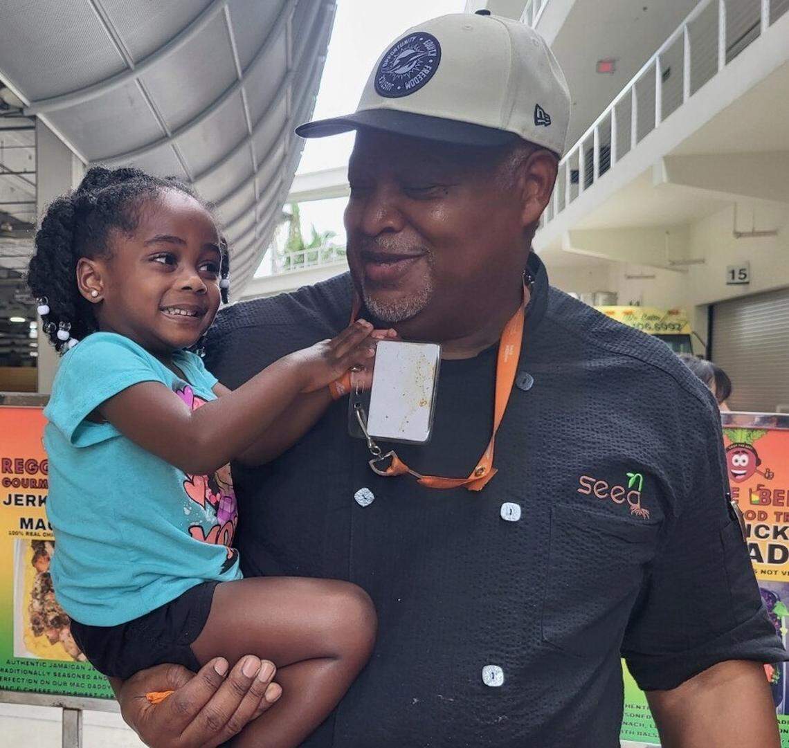 Herb Coleman holds his granddaughter at Hard Rock Stadium.
