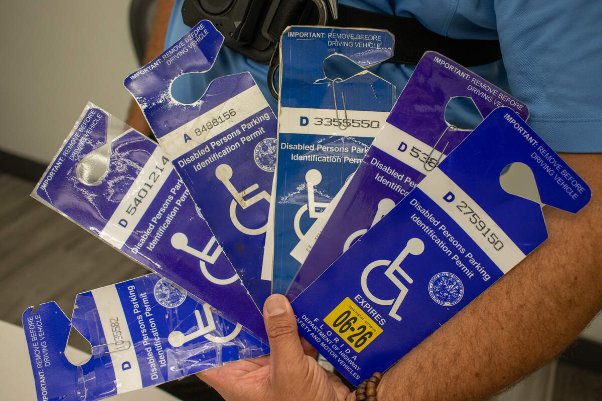 A Coral Gables parking enforcement officer shows some of the fraudulent disability parking permits he’s recently confiscated across the city.