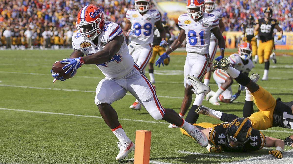 In this file photo, Florida Gators running back Mark Thompson (24) dives into the end zone past Iowa Hawkeyes linebacker Ben Niemann (44) and defensive back Joshua Jackson (15) for Florida’s first touchdown of the game during the Outback Bowl on Monday, Jan. 2, 2017 at Raymond James Stadium in Tampa, Fla.
