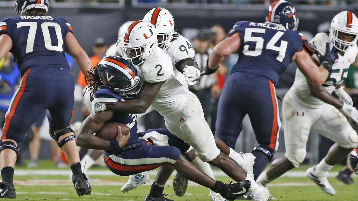 Miami Hurricanes defensive back Trajan Bandy (2) defensive lineman Trevon Hill (94) sack Virginia Cavaliers quarterback Bryce Perkins (3) in the fourth quarter as the University of Miami host the Virginia Cavaliers at Hard Rock Stadium in Miami Gardens on Friday, October 11, 2019.