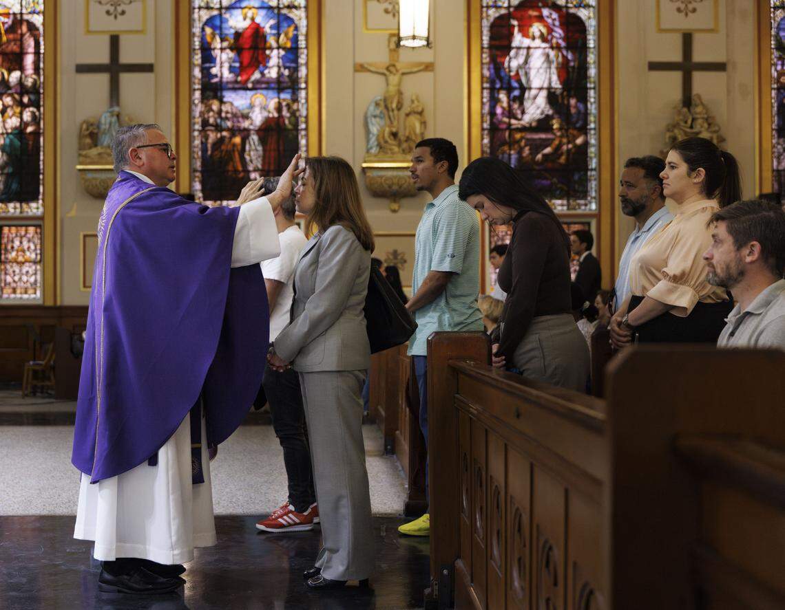 Fr. Orlando Portalatin, a Jesuit priest, places ashes on a woman's forehead during Ash Wednesday mass on Wednesday, Feb. 18, 2026, at Gesu Catholic Church in downtown Miami. 