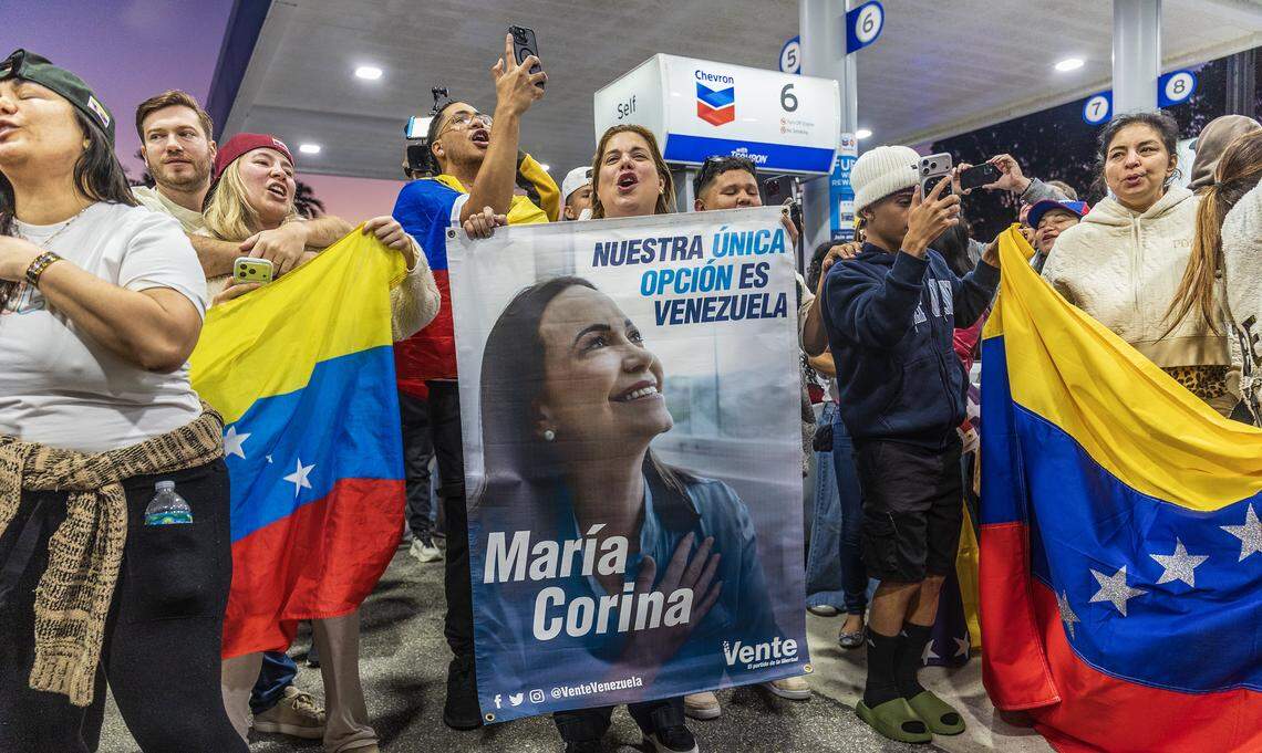 Lisbeth García displays a banner with a picture of the opposition leader María Corina Machado as she joined a group of Venezuelan exiles living in South Florida celebrating outside of El Arepazo in Doral, Florida, after the United States attacked Venezuela and captured Venezuelan leader Nicolás Maduro, on Jan. 3, 2026.