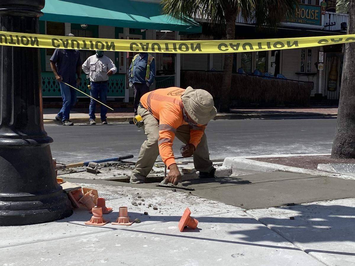 A workman smooths cement on a sidewalk off Key West’s Duval Street on May 22, 2020.