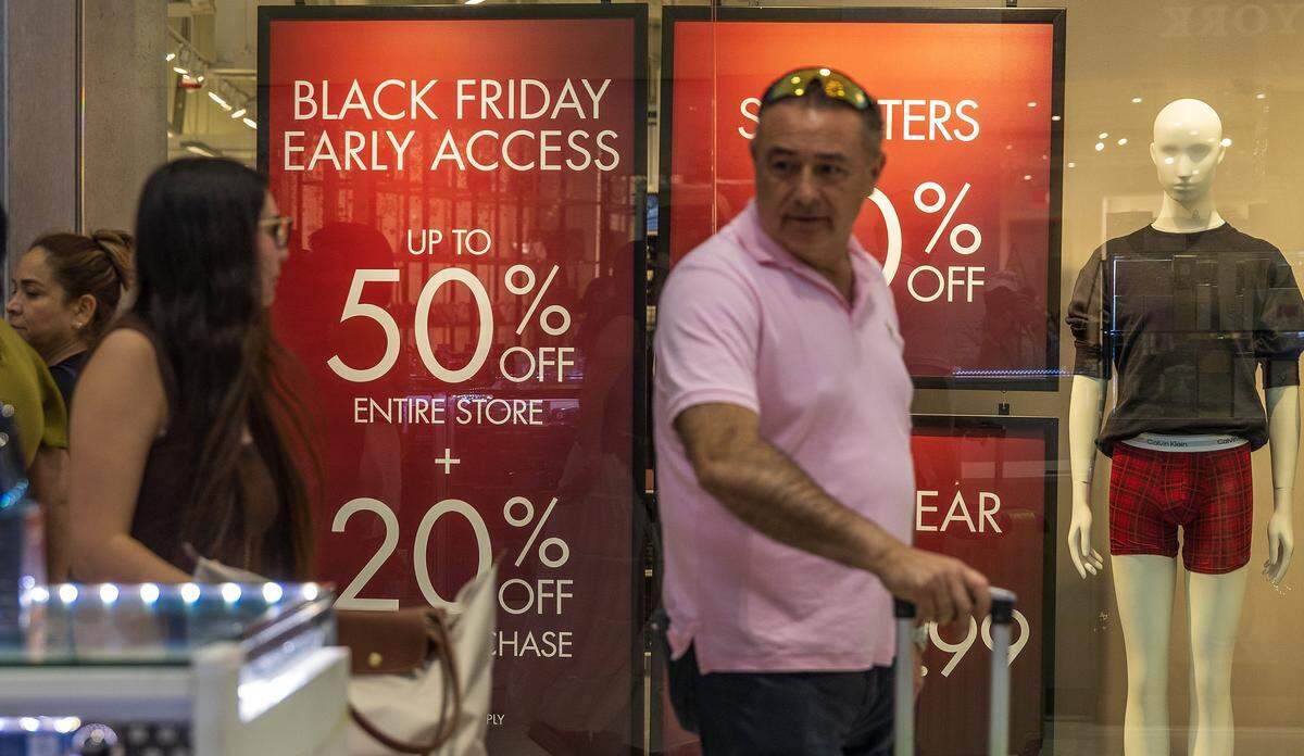 Shoppers walk by sales discount banners at the Calvin Klein’s store in the Dolphin Mall in Miami, ahead of the Black Friday Sale event, on Friday, Nov. 21, 2025.