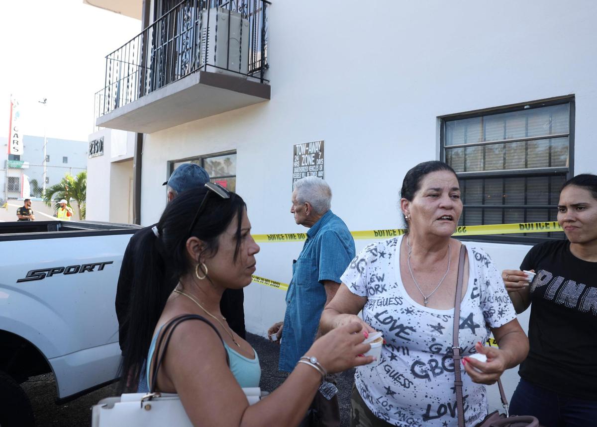 María Magdalena Hernández, de 61 años, centro, reparte café a otros residentes mientras esperan respuestas después de que un pasillo del segundo piso se derrumbara esta mañana. El edificio de Palm Avenue, en Hialeah, se declaró “inseguro” este lunes 31 de octubre de 2022.