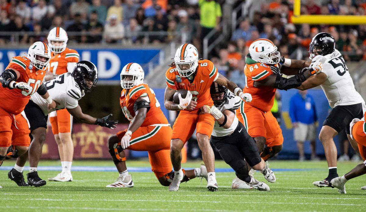 Miami Hurricanes running back Damien Martinez (6) runs with the ball as Iowa State Cyclones linebacker Kooper Ebel (47) tries to tackle him in the second half of their Pop-Tarts Bowl football game at the Camping World Stadium on Saturday, Dec. 28, 2024, in Orlando, Fla.