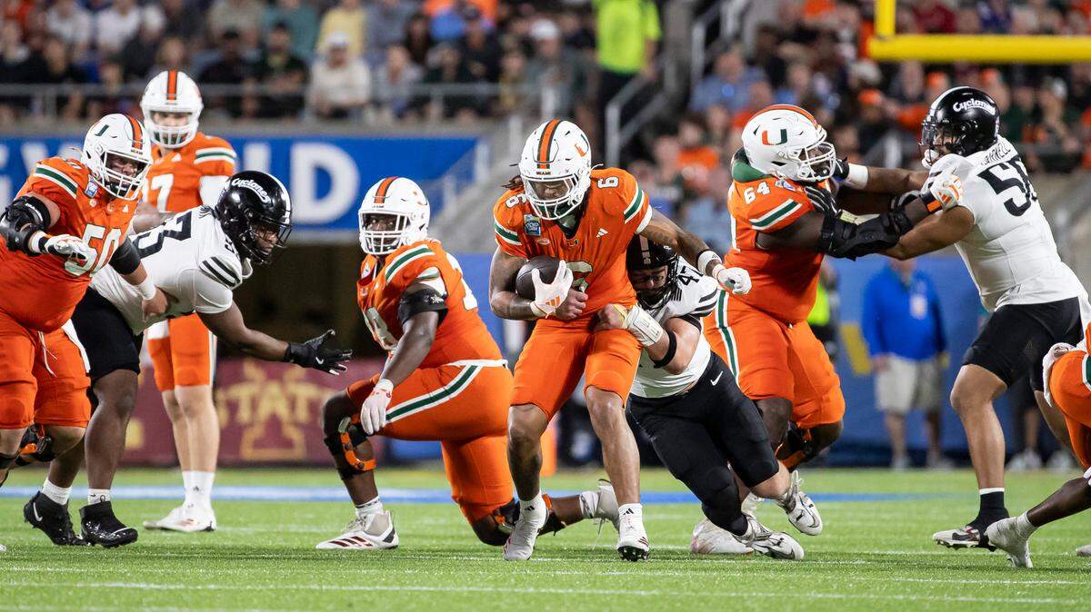 Miami Hurricanes running back Damien Martinez (6) runs with the ball as Iowa State Cyclones linebacker Kooper Ebel (47) tries to tackle him in the second half of their Pop-Tarts Bowl football game at the Camping World Stadium on Saturday, Dec. 28, 2024, in Orlando, Fla.