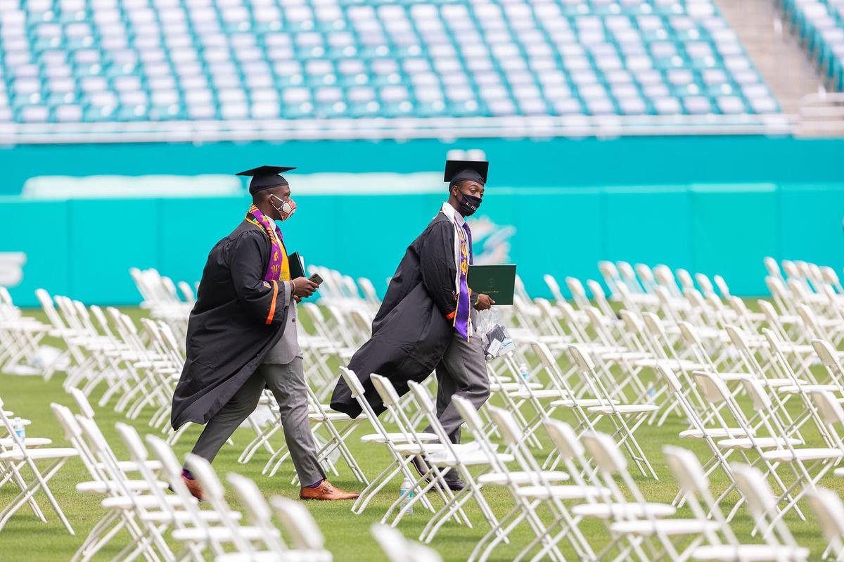 Two students walk across the field at the Hard Rock Stadium in Miami Gardens where the University of Miami spring commencement ceremonies took place on Friday, May 14, 2021.