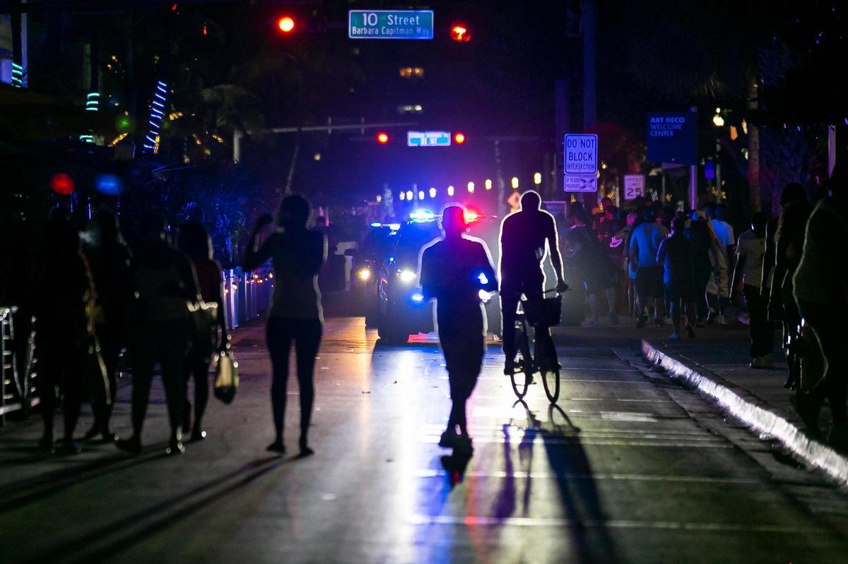 Beach goers make their way off Ocean Drive as police enforce the 8 p.m. spring break curfew in Miami Beach, Florida on Friday, March 26, 2021.