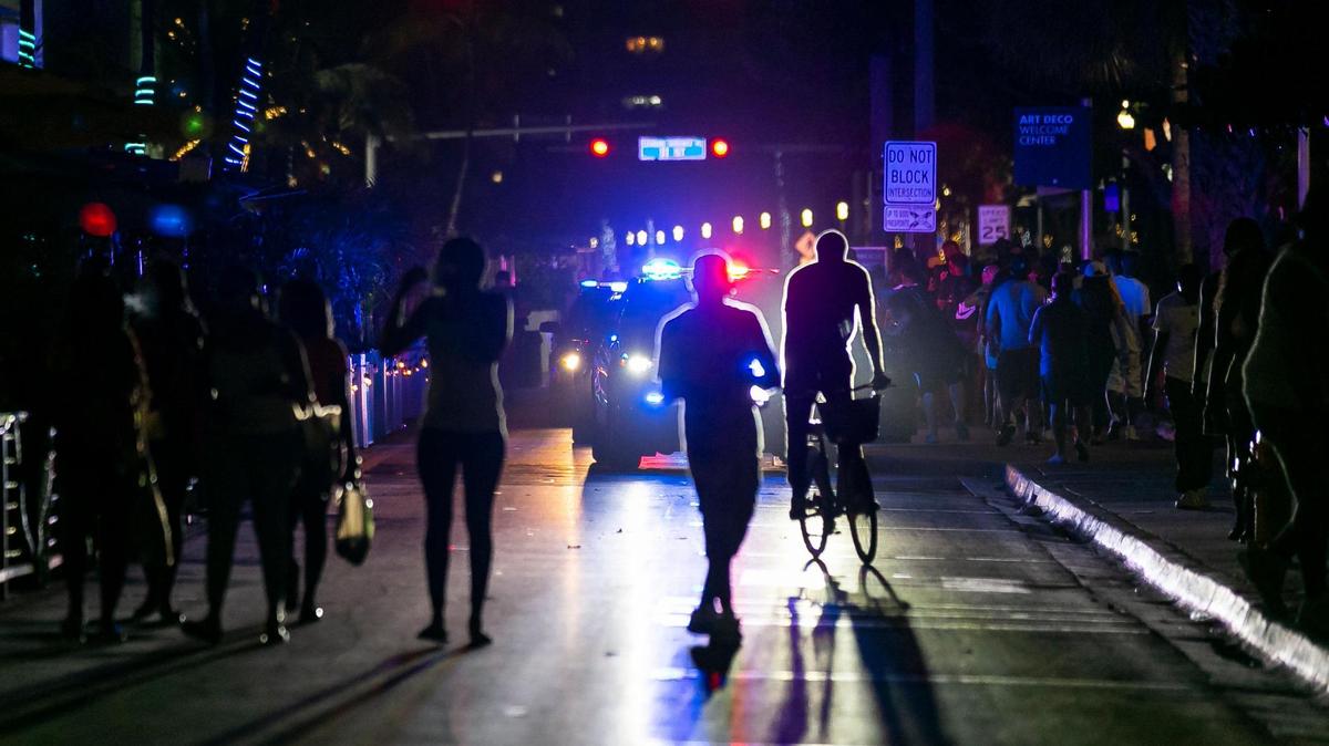 Beach goers make their way off Ocean Drive as police enforce the 8 p.m. spring break curfew in Miami Beach on Friday, March 26, 2021.
