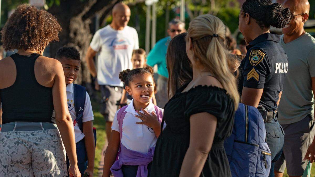Students and parents wait to cross Prairie Avenue to enter North Beach Elementary in Miami Beach, Florida on the first day of school Aug. 17, 2022.