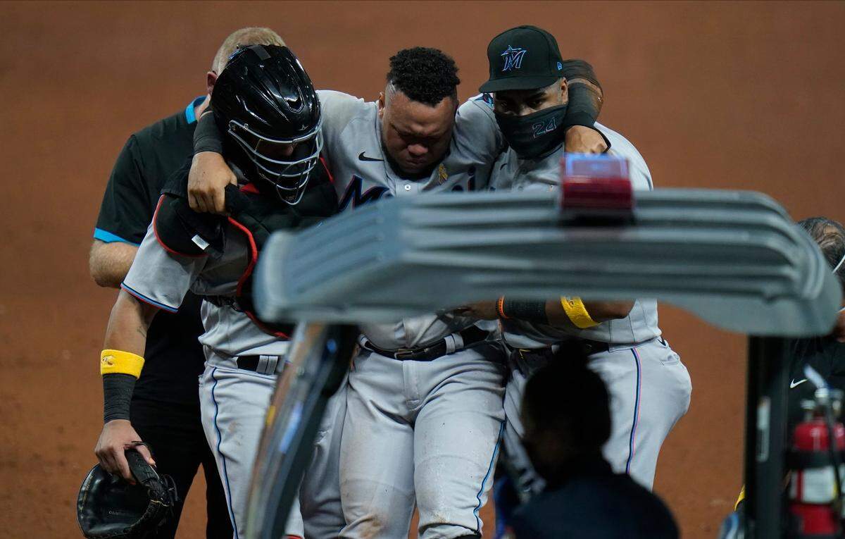 Miami Marlins catcher Jorge Alfaro, left, and first baseman Jesus Aguilar, right, help Harold Ramirez to an awaiting ambulance after he injured himself running out a ground ball against the Tampa Bay Rays during the fifth inning of a baseball game Saturday, Sept. 5, 2020, in St. Petersburg, Fla. (AP Photo/Chris O’Meara)