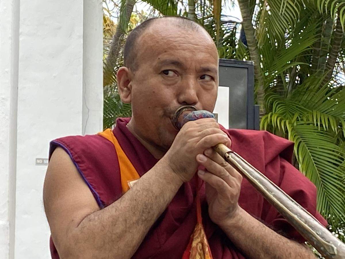 A Tibetan monk plays the long horn, or dungchen on Jan. 19, 2020, outside a church on Duval Street in Key West.