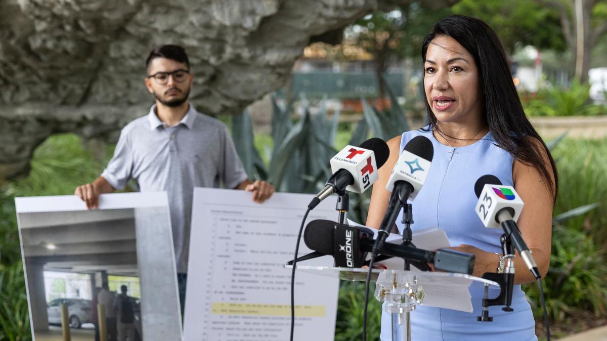 Steven Rivero holds signs as Irina Vilarino, co-owner of the Las Vegas Cuban Cuisine restaurant and a candidate for Doral City Council Seat 3, holds a press conference at Downtown Doral Park on Wednesday, Aug. 28, 2024, in Doral, Florida.
