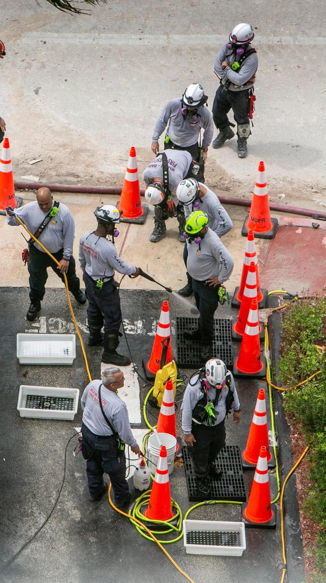 Rescue workers get cleaned off at a cleaning station on Tuesday, July 13, 2021, at the end of their shift at the site of the Champlain Towers South collapse.