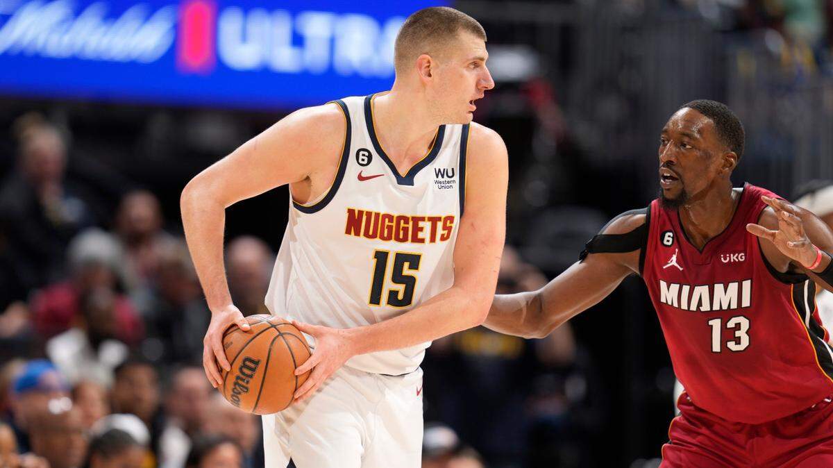 Denver Nuggets center Nikola Jokic, left, looks to pass the ball as Miami Heat center Bam Adebayo defends in the first half of an NBA basketball game Friday, Dec. 30, 2022, in Denver.