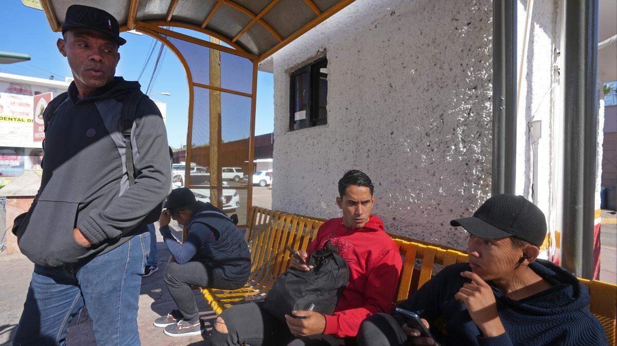 May 12, 2023; Nogales, Sonora, Mexico; Wilmer Rafael Carson Castillo, left, who has been on an eight-month journey from his home country of Venezuela, stands outside of the U.S. Customs and Border Protection Dennis DeConcini Port of Entry where he has an asylum appointment set up through CBP One. Mandatory Credit: Joe Rondone-USA TODAY NETWORK