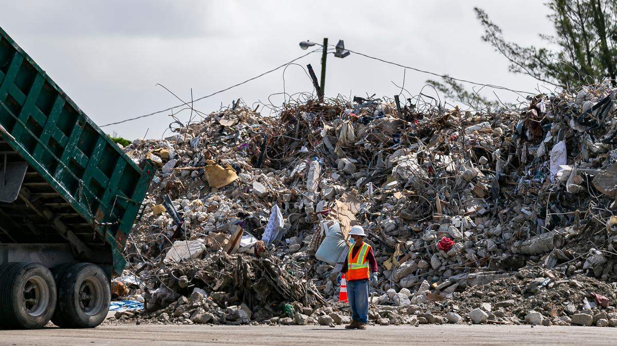 A truck drops debris and rubble from the collapsed Champlain Towers South inside a lot near the Miami International Airport at the intersection of Milam Dairy Road and Northwest 12th Street in Miami on Saturday, July 10, 2021.