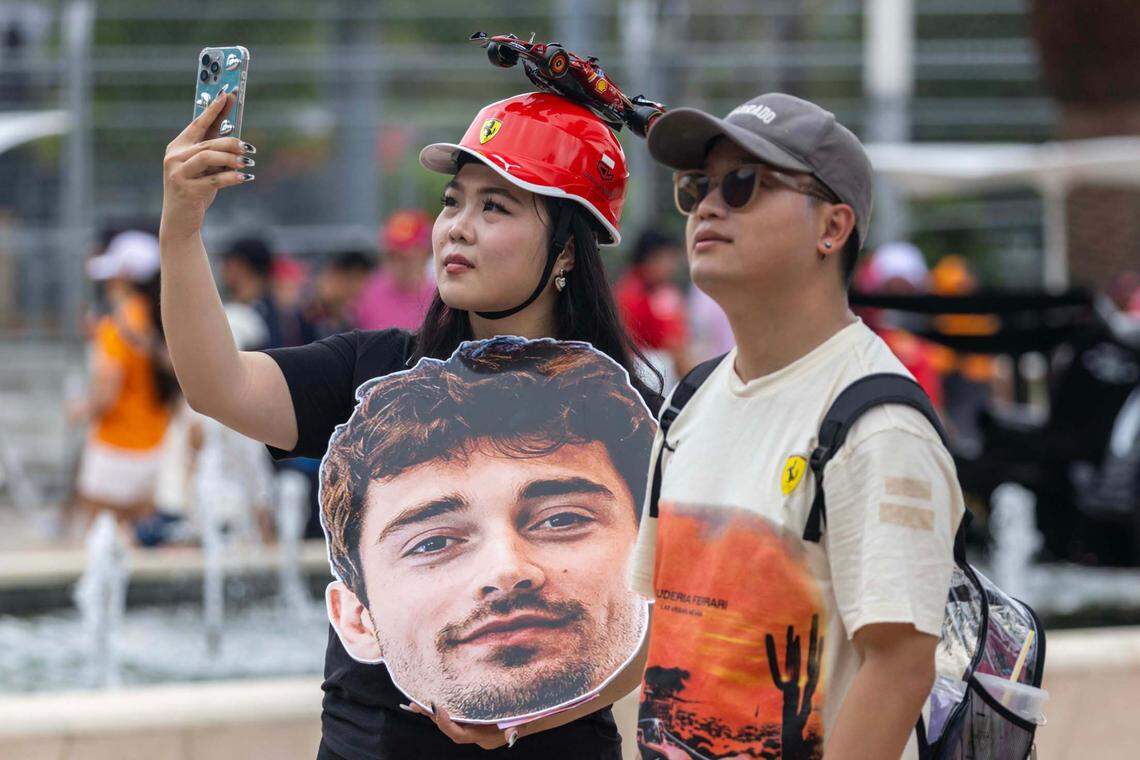 Formula One fan and Los Angeles resident Ziwei Zhou, 30, left, takes a cellphone photo alongside Yang Zheng, 30, right, while holding a giant cutout of Ferrari driver Charles Leclerc inside the Miami International Autodrome ahead of the Formula One Miami Grand Prix at the Miami International Autodrome on Sunday, May 4, 2025, in Miami Gardens, Fla.