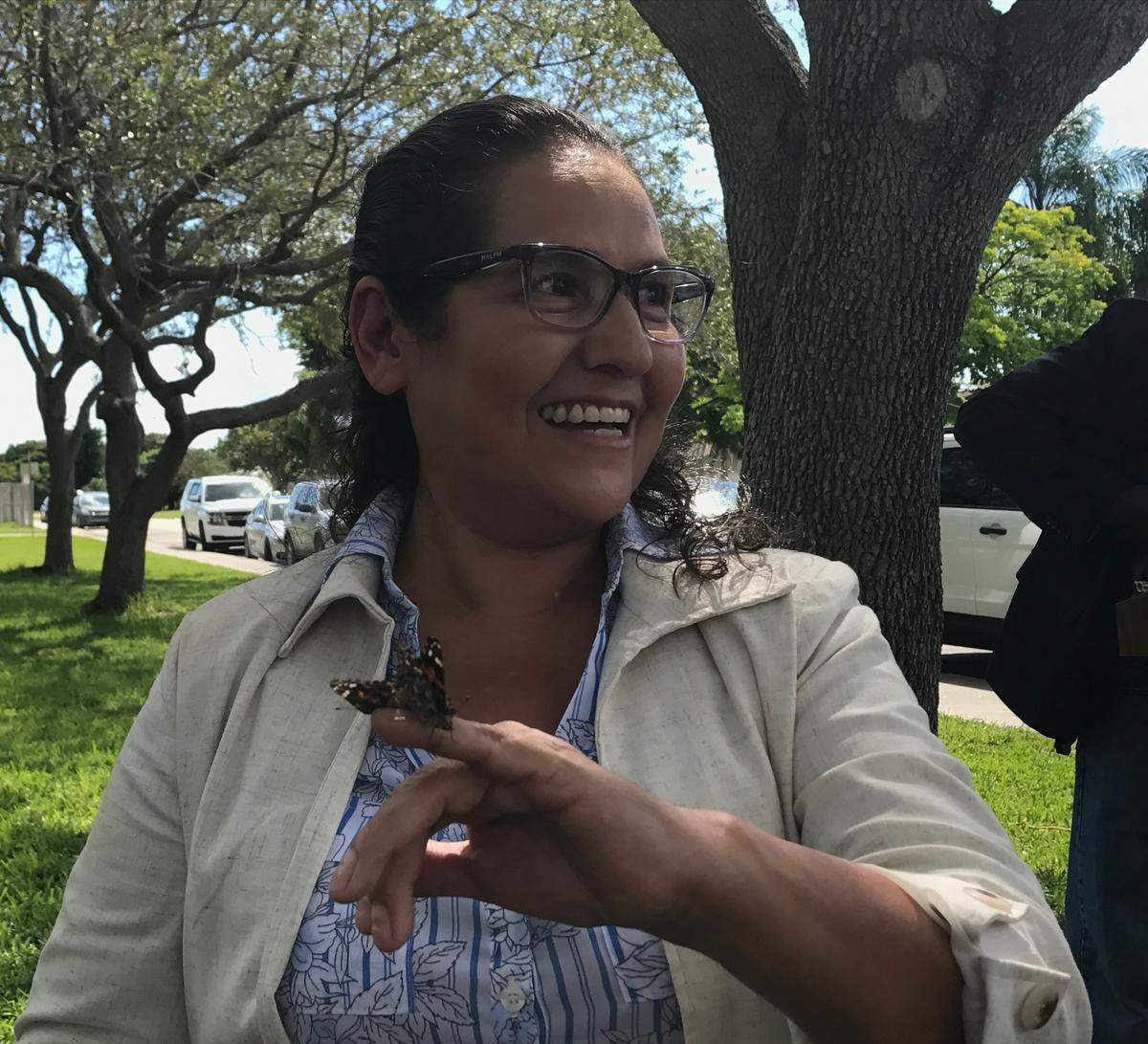 Maria Gough laughs while a butterfly clings to her finger during a ceremony Thursday, Sept. 20, 2018, honoring her son, Jaime Gough, with a street sign in Palmetto Bay with his name on it.