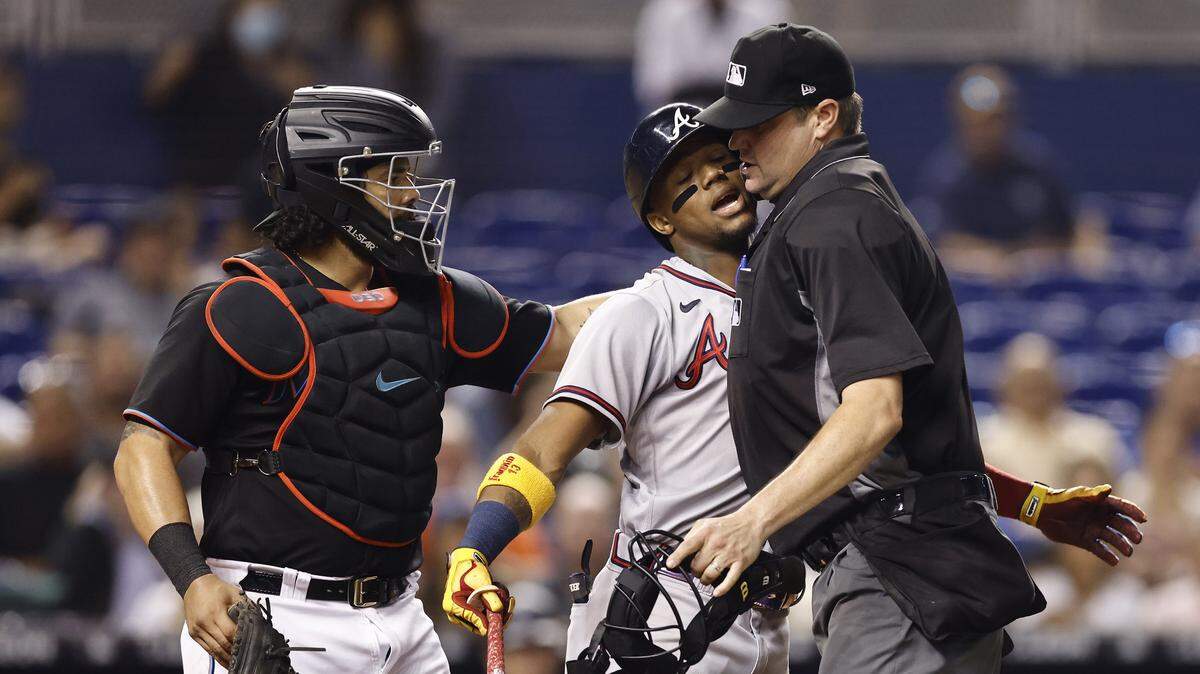MIAMI, FLORIDA - JULY 09: Umpire Jordan Baker #71 holds back Ronald Acuna Jr. #13 of the Atlanta Braves after he was hit by a pitch from Anthony Bender #80 of the Miami Marlins (not pictured) during the seventh inning at loanDepot park on July 09, 2021 in Miami, Florida. (Photo by Michael Reaves/Getty Images)