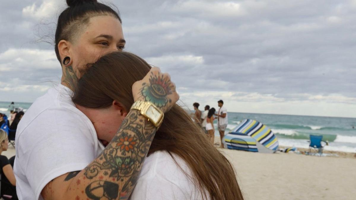 Chloé Castaneda, left, hugs her younger sister Hailey Clements, as family and friends gather for a memorial service for their brother Victor Castaneda who lost his life while swimming in Miami Beach. The service is being held at the place where Victor was last seen, South Pointe Beach.