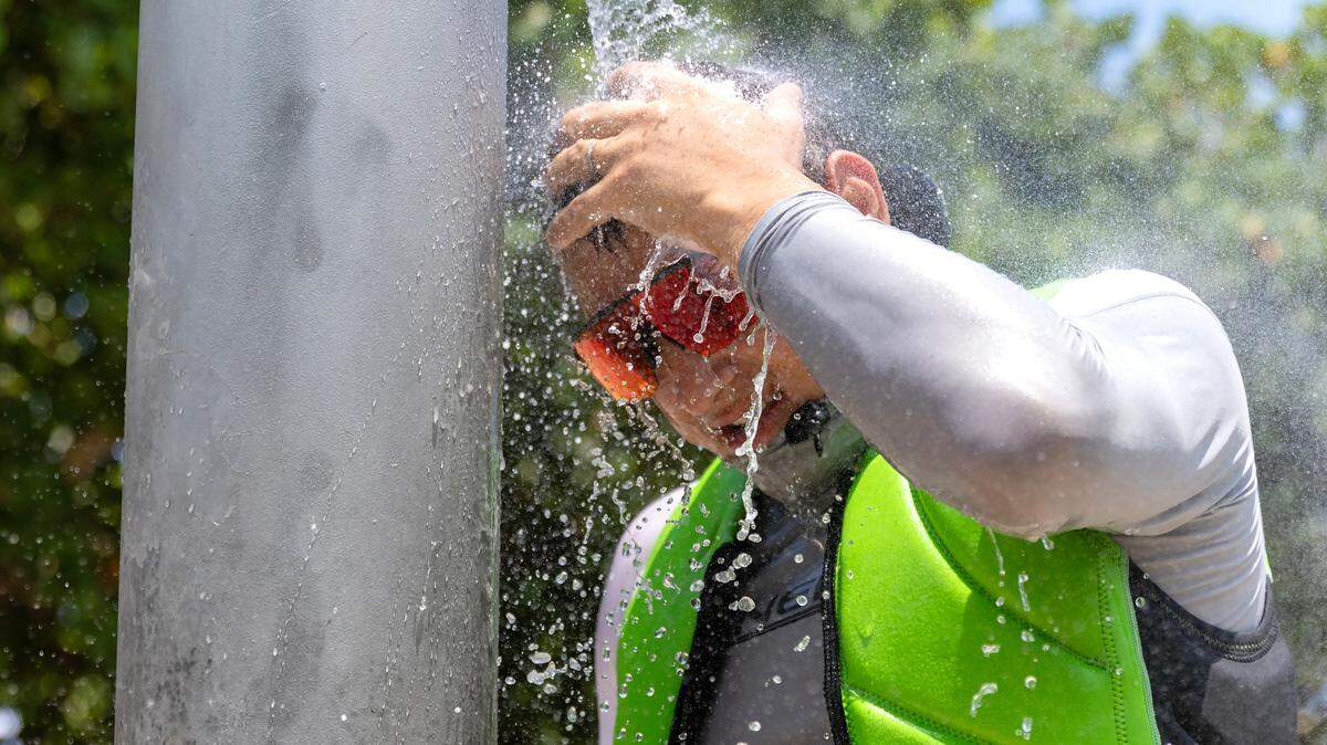 Beachgoer Sergei lazovskiy cools off under the shower after enjoying the sunny and hot day at  Haulover Park Beach in 2024.