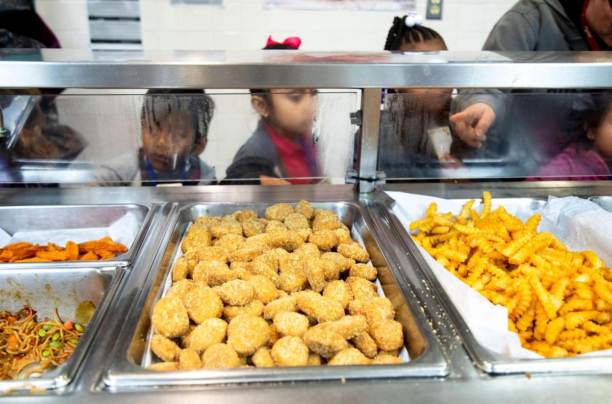 Niños de un campamento secreto para inmigrantes en el sur de Miami-Dade hacen fila en la cafetería de la escuela.