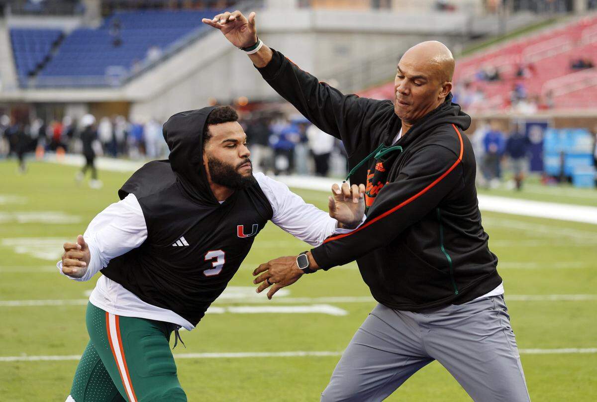 Miami Hurricanes defensive lineman Akheem Mesidor (3) works out with Defensive Line Coach Jason Taylor before the start of an NCAA football game against the Southern Methodist University Mustangs at Gerald Ford Stadium on Saturday, November 1, 2025, in Dallas, Texas.
