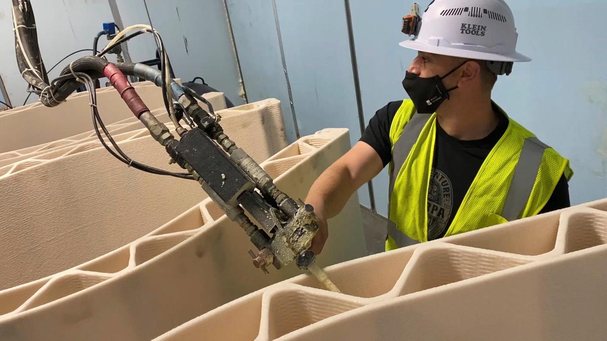 Mighty Buildings production manager Yonah Naftaly shows a machine that fills 3D-printed wall panels with insulating foam on Wednesday, March 17, 2021, in Oakland, Calif. The printer can produce the entire exterior shell of a studio home or individual wall panels that can easily assembled with simple tools, the company said. Mighty Buildings is now producing 350-square-foot backyard studios, known in the industry as “accessory dwelling units,” that can be used as extra bedrooms, playrooms, gyms or home offices.