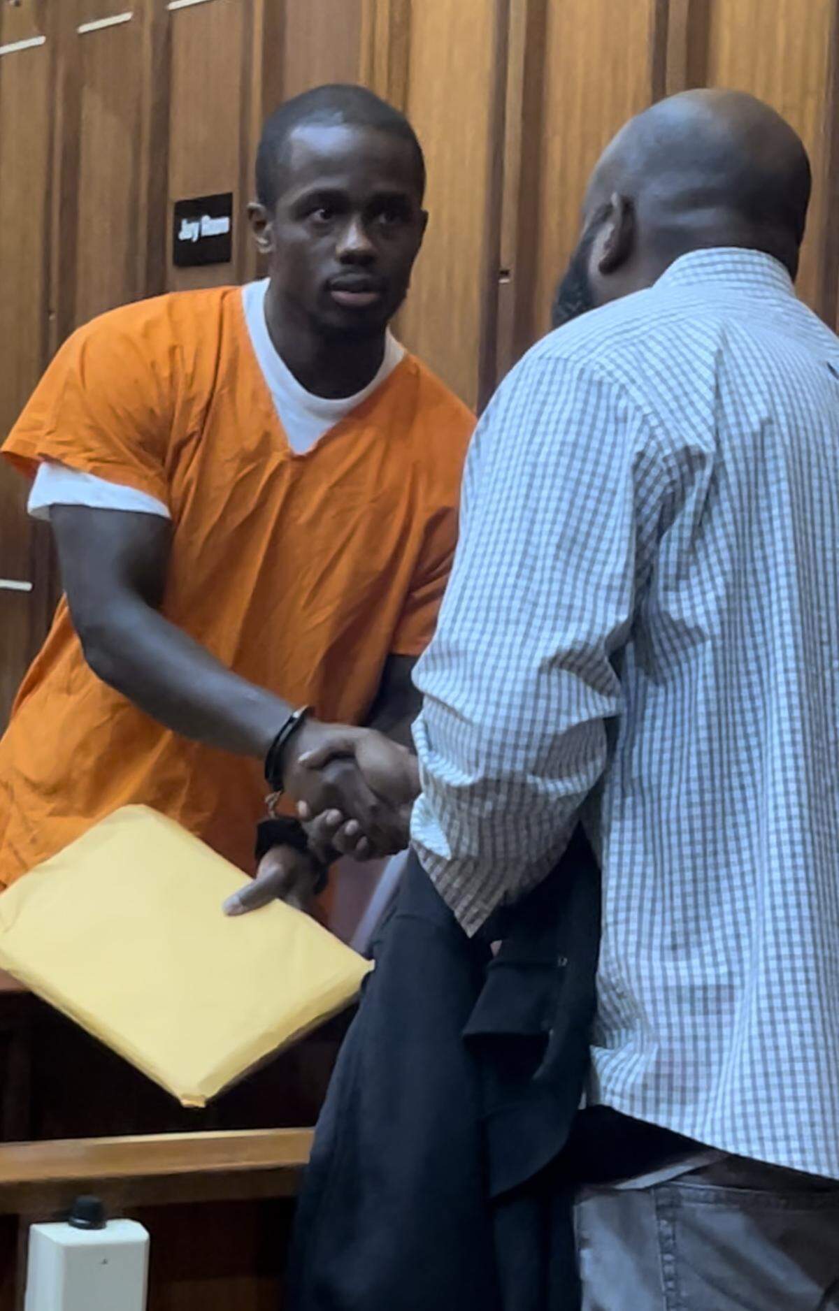 Emmanuel Jean, who was released from prison 16 years after being wrongfully accused, shakes the hand of a witness whose affidavit helped free him during an April hearing in front of Miami-Dade Circuit Court Judge Miguel De La O.